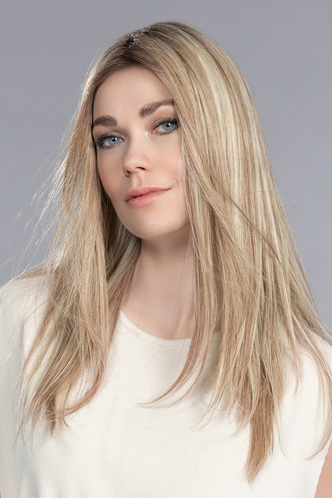 Woman wearing Boheme, a long human hair wig, in the color Sandy Blonde Rooted.