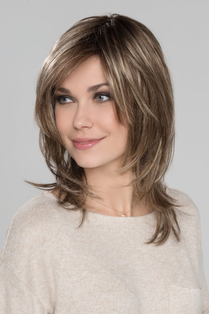 Side view of model showing the choppy face framing layers on a shoulder length wig.