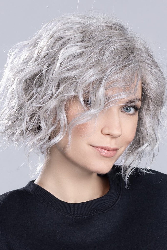 Model wearing a wig in a blend of pure white, silver white, and grey with a very subtle touch of light brown.