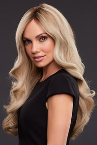 Elegant woman gently looking forward while wearing a full luxuriously long blonde wig that falls down to her waist.