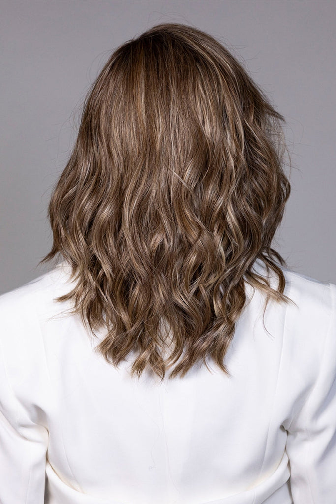 Back of model wearing a long wavy wig.