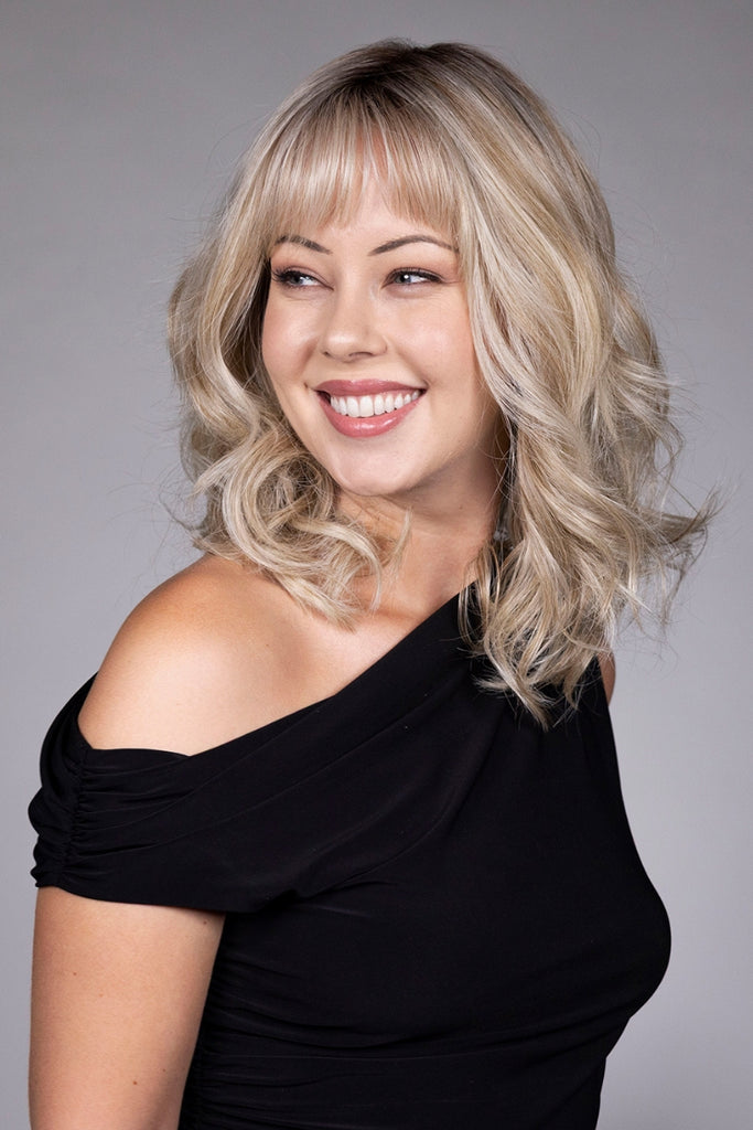 Woman wearing a shoulder-length, wavy style with bangs.