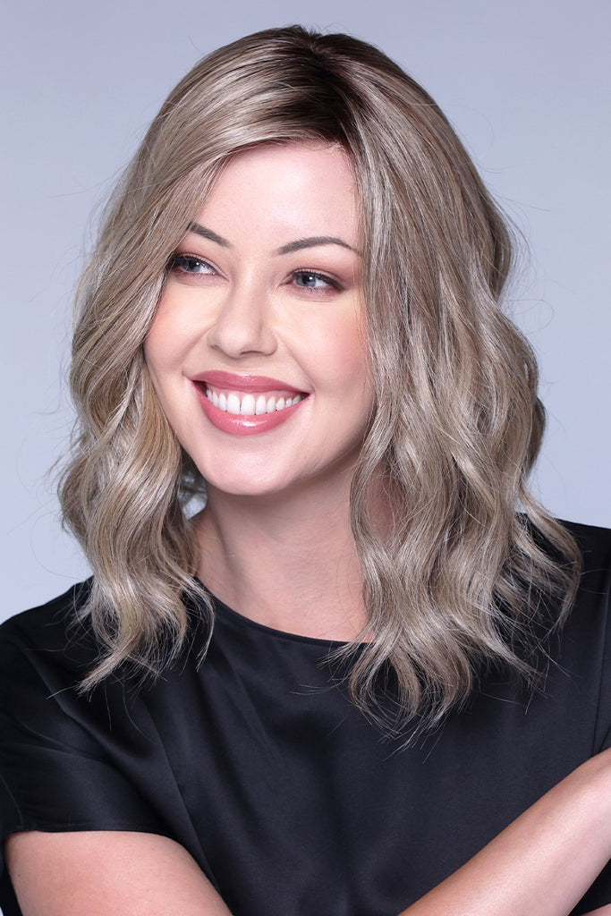 Model smiling to the side while wearing a wig in the color Shaken Oatmilk Blonde R.