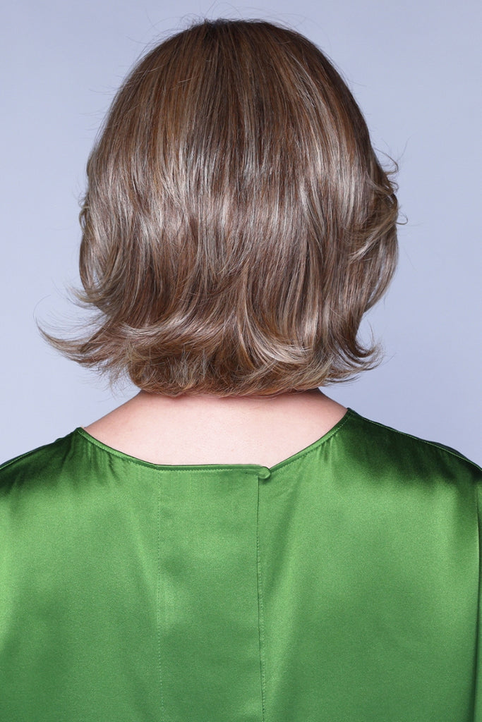 Back view of a wig in a medium brown color with light blonde highlights and a darker root.