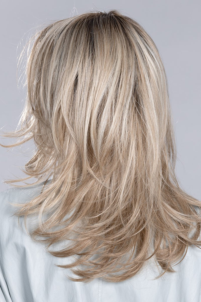 Back of wig in a a blend of warm and cool toned blondes with dark roots.