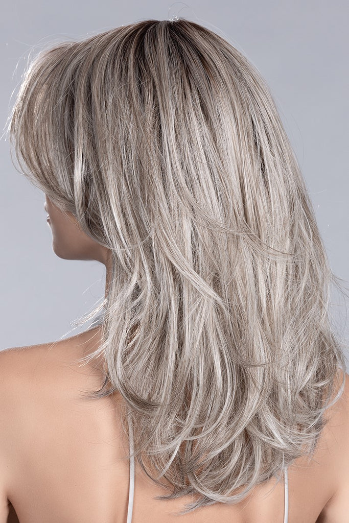 The back of women wearing a wig in a blend of platinum blonde, white and grey with darker rooting.