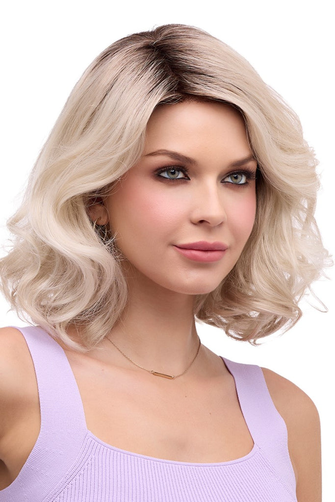 Side view of model styling an elegant shoulder length wig with large waves.