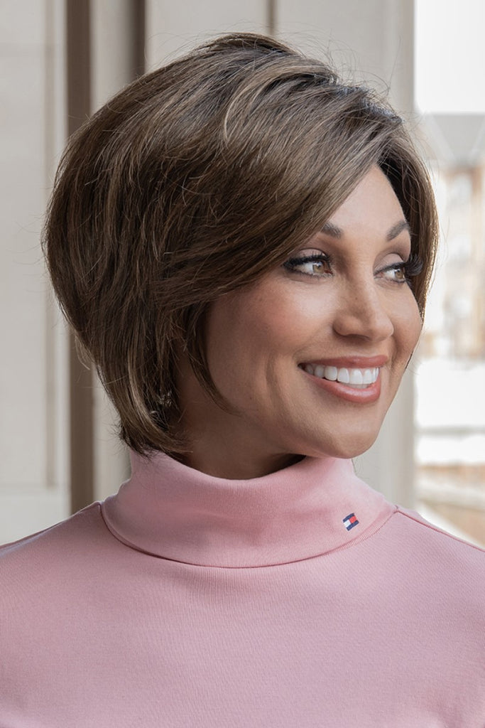 Side view of women wearing a chin length voluminous wig with face framing layers.