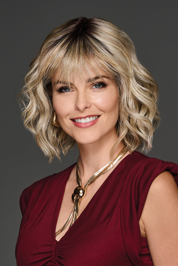 Front view of woman wearing a medium length wig with bangs.