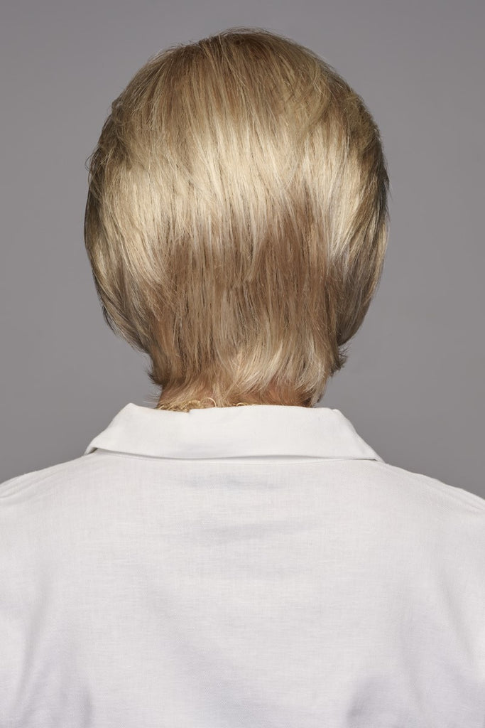 Back of model wearing a wig with razor cut back and sides. 