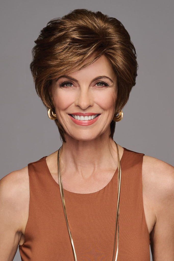 Model wearing a softly waved layered wig with bangs.