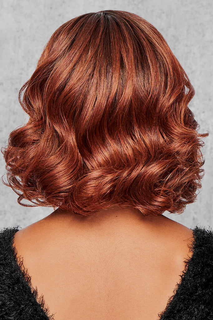 Back photo of a wig with soft curls, in the color Rooted Dark Copper. 