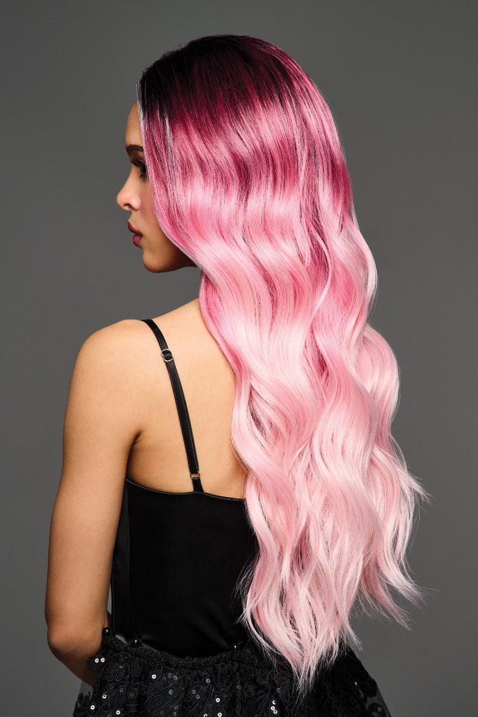 Side of women wearing a layered dark rooted pink wig.