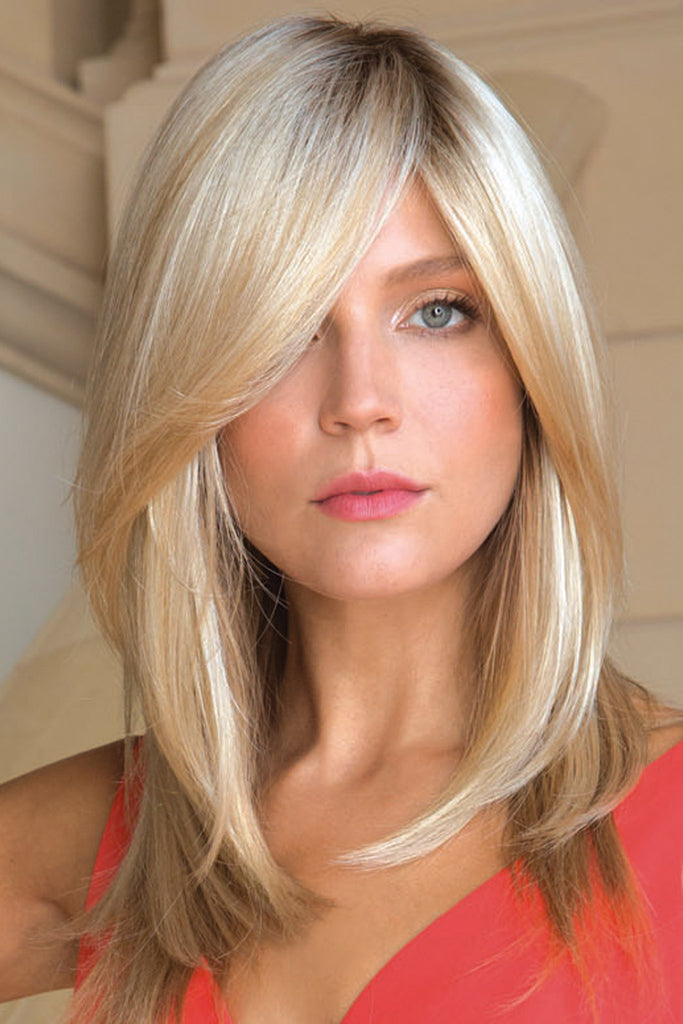 Woman looking into the camera showing off her wig Milan by Noriko, elegant layered blonde wig for women.