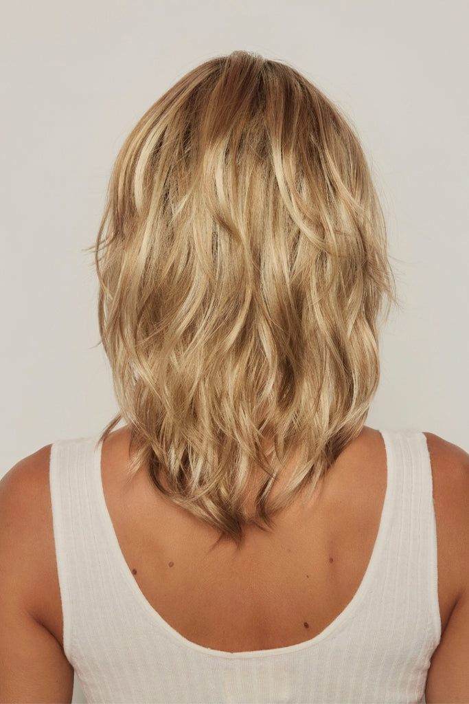 Back of model wearing a layered wavy wig.