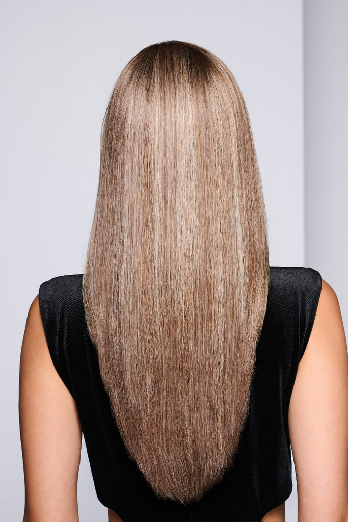 Model styling a long, layered wig in a dimensional blonde.