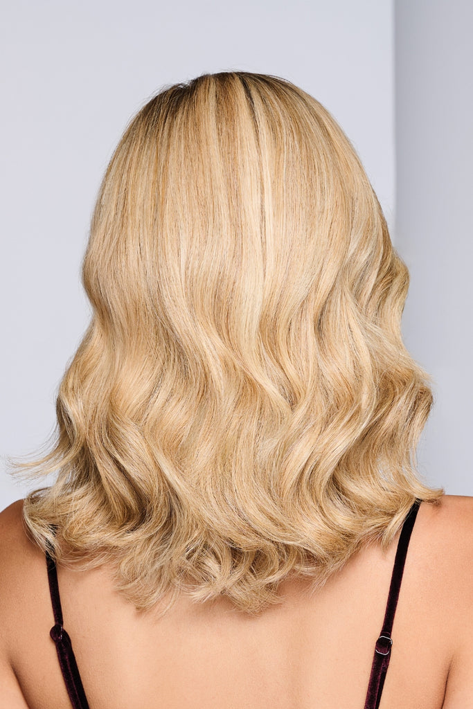 Back of model wearing a wavy, shoulder-length piece in a dimensional blonde color.