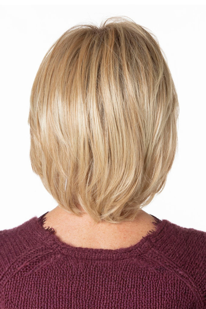 Back of woman wearing a layered bob in a dimensional blonde color with shaded roots.